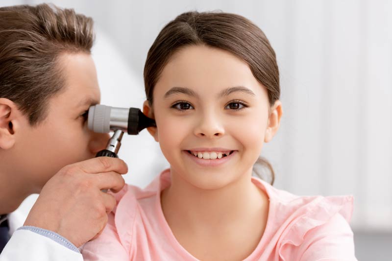 physician examining ear of cheerful kid