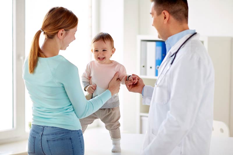 Happy woman and baby with ear infection and doctor at clinic