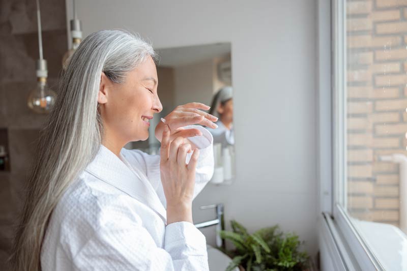 Portrait of smiling lady in the bathroom smelling her wrist