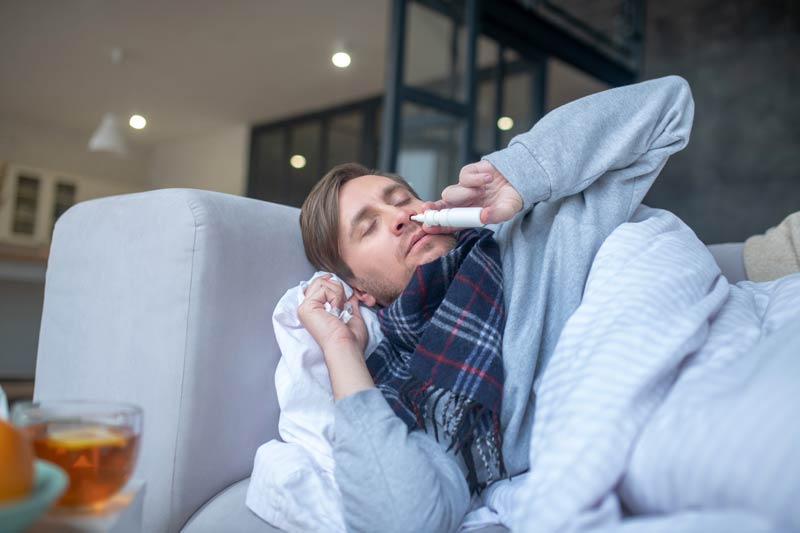 Man laying on couch with nasal spray