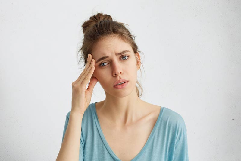 Young woman holding hand on head with ear pain