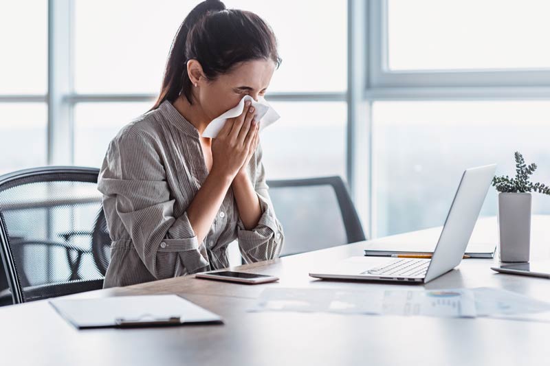 Sick woman working with postnasal drip blowing nose