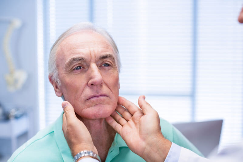 doctor examining senior patients neck