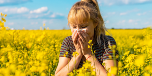 Woman sneezing into tissue surrounded by pollen due to fall allergies