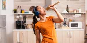 Woman with headphones on and singing into a spatula