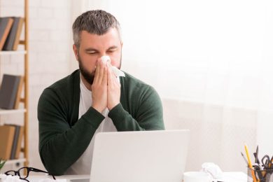 Caucasian male blowing nose