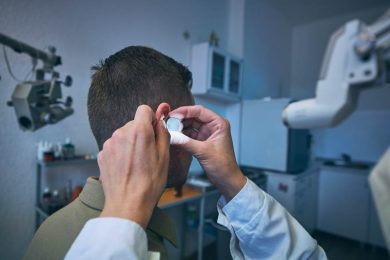 Doctor doing ear examination of young male patient before ear wax removal