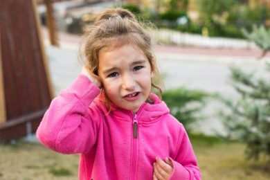 Little girl with infection holding ear in pain