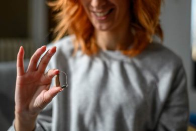 Young woman holding hearing aid